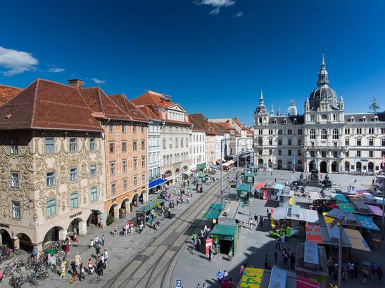 Blick von Oben auf den Hauptplatz von Graz. Menschen tummeln sich am Platz.